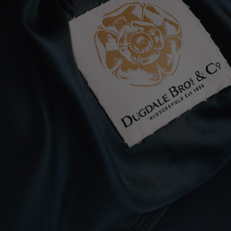 The gold Dugdale Bros and Co rose label resting on dark green cloth